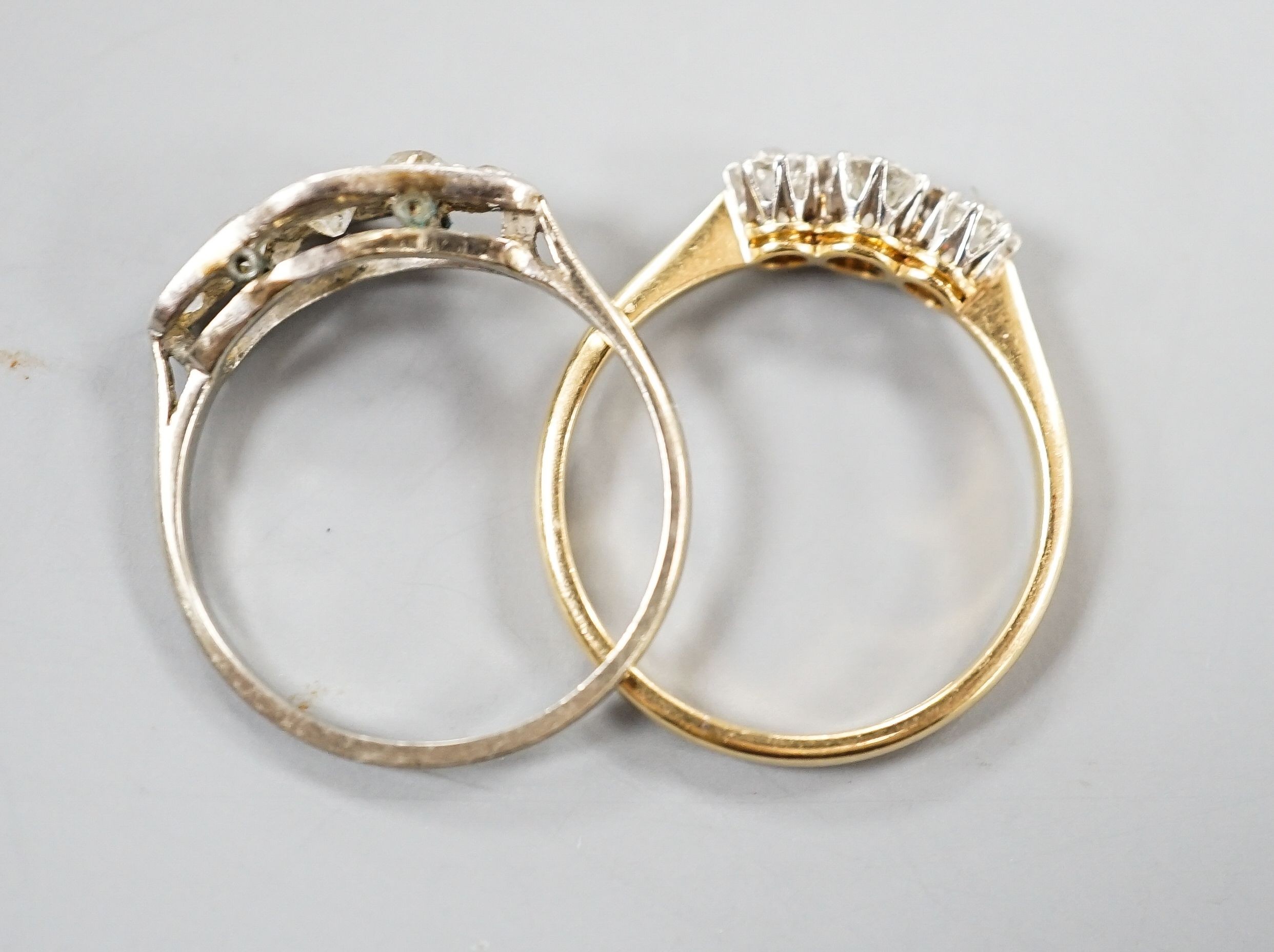 An 18ct and three stone diamond ring, size M and a white metal and graduated five stone diamond set half hoop ring, size M, gross weight 3.8 grams.